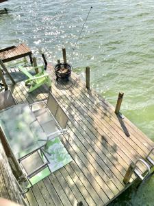 eine Anlegestelle mit Grill und Stühlen auf dem Wasser in der Unterkunft Lake Front Home Near Peek'n Peak in Findley Lake