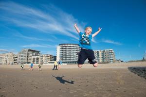 Ein kleiner Junge, der am Strand in die Luft springt. in der Unterkunft Vayamundo Oostende in Ostende