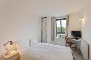 a bedroom with a bed and a desk with a computer at Breathtaking 2 Bedroom Apartment with Balcony near Stoke Newington in London