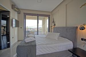 a bedroom with a white bed with a balcony at Villa Popi - modern villa with private pool by PosarelliVillas in Galatás +15 photos
