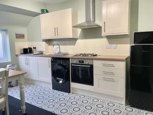 a kitchen with white cabinets and a washer and dryer at Bare Village Holiday Apartment in Bare