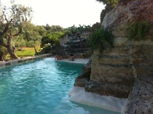 ファザーノにあるMasseria Pelosella B&Bの水中に座る人々と一緒にプール