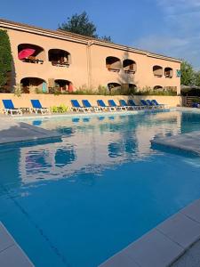 a swimming pool with blue chairs and a building at Les Cigalous in Salavas