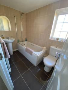 a bathroom with a tub and a toilet and a sink at Flint Lodge in Peacehaven