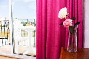 a vase with flowers on a table in front of a window at Hotel Oasis Atalaya in Conil de la Frontera