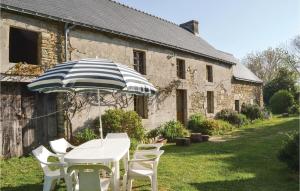 a table and chairs with an umbrella in front of a building at Stunning Home In Moelan Sur Mer With 3 Bedrooms in Moëlan-sur-Mer