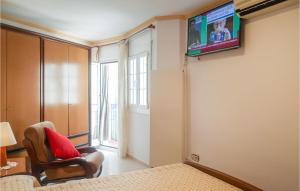 2 Bedroom Amazing Apartment In Tossa De Mar في توسا ذي مار: غرفة بها تلفزيون على الحائط وكرسي