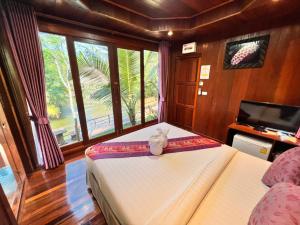 a bedroom with a bed and a tv and windows at บ้านสวนในฝัน-ตลาดน้ำท่าคา in Samut Songkhram