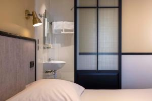 um quarto com uma cama, um lavatório e uma janela em Hotel de l'Aqueduc em Paris