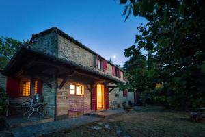 a stone house with red doors and windows at night at Agriturismo fringuello - Sofora in Cortona