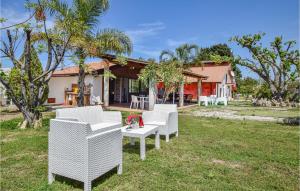 a group of white chairs in the yard of a house at Nice Home In Torranova With Kitchen in Torrenova