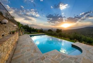 a swimming pool with a sunset in the background at Agriturismo fringuello - Sofora in Cortona