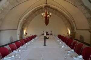 einen langen Tisch in einem Zimmer mit roten Stühlen und einem Kronleuchter in der Unterkunft Hotel Los Leones - Adults Only in Rubielos de Mora