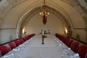 a long table in a room with red chairs and a chandelier at Hotel Los Leones - Adults Only in Rubielos de Mora