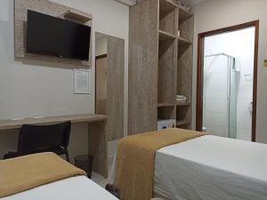 a hotel room with two beds and a tv at Pousada Della Nonna in Presidente Prudente