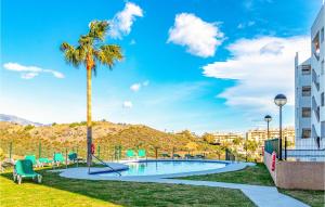 a swimming pool with a palm tree and a building at Stunning Apartment In Mijas Costa in Mijas Costa
