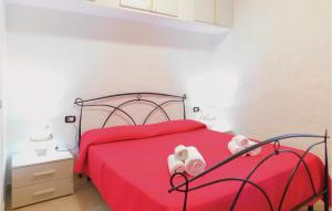 a bedroom with a red bed with pink sheets and white towels at Nice Apartment In Gonnesa With Wifi in Gonnesa