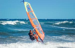 a man riding a surfboard with a sail on the ocean at Villa 6 in Villaputzu