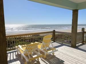 two chairs sitting on a porch overlooking the beach at 1 Naut On Call home in Crystal Beach