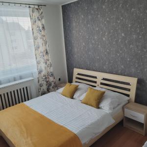 a bedroom with a bed with white sheets and yellow pillows at Apartmán ZUZKA in Veľká Lomnica