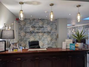 a reception desk with a sign on a wall at The Wildings Hotel & Tudno's Restaurant in Llandudno