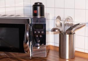 eine Mikrowelle mit einem Behälter mit Küchenutensilien in der Unterkunft Ferienwohnung Bruderwald in Bamberg