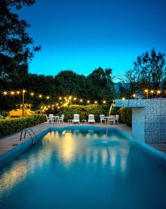 una piscina con mesas y sillas por la noche en Costabela Apart Hotel e Pousada, en Ilhabela