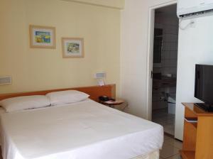 1 dormitorio con 1 cama blanca y TV en Flats Praia Mansa, en Fortaleza