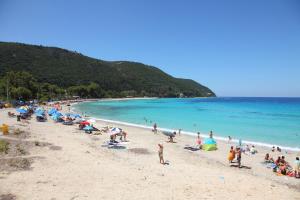 eine Gruppe von Menschen am Strand mit dem Meer in der Unterkunft Kydonies Villas in Lefkada Town