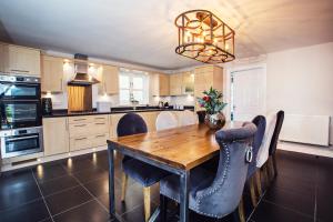 a kitchen with a wooden table and chairs at Larchfield Grange, Luxury House with Stunning Views in Abergavenny