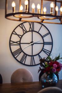 a large clock on a wall with a vase of flowers at Larchfield Grange, Luxury House with Stunning Views in Abergavenny