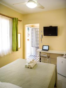 1 dormitorio con 1 cama y escritorio con ordenador portátil en Costabela Apart Hotel e Pousada, en Ilhabela