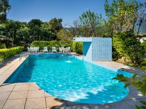 a swimming pool with tables and chairs in a yard at Costabela Apart Hotel e Pousada in Ilhabela