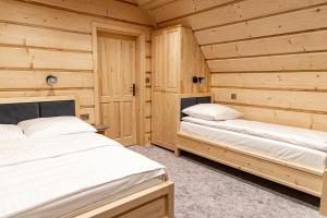 two beds in a room with wooden walls at Bajka Chateau in Czarna Góra