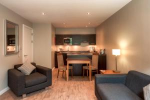 a living room with a table and chairs and a kitchen at PREMIER SUITES Manchester in Manchester