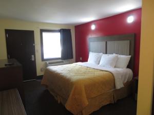 ein Hotelzimmer mit einem Bett mit einer roten Wand in der Unterkunft Brick Motor Inn in Brick