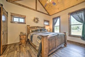 a bedroom with a wooden bed in a room with windows at Ouachita Mtn Home Near ATV and Hiking Trails! in Big Cedar