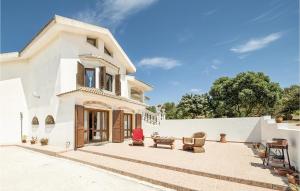 a white house with chairs and a table on a patio at Villa Anna in Sennori