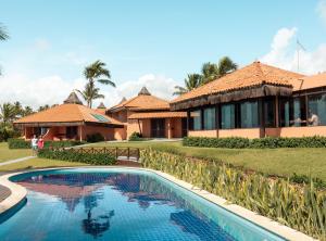 a resort with a swimming pool in front of a building at Pousada Tabapitanga in Porto De Galinhas