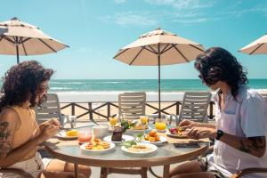 Dos mujeres sentadas en una mesa con comida en la playa en Pousada Tabapitanga en Porto De Galinhas