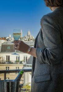 a woman holding a glass of wine on a balcony at Hotel Litteraire Le Swann, BW Premier Collection in Paris