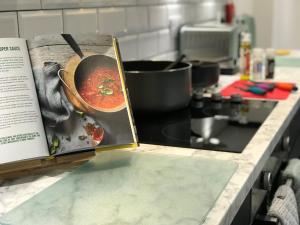 książkę siedzącą na blacie kuchennym z garnkiem zupy w obiekcie Stylish modern 3-bed house nr Manchester city ctr w mieście Whitefield