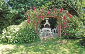 a garden with a chair under an arch with roses at Holiday Home Saint Jean-Trolimon - 02 in Saint-Jean-Trolimon