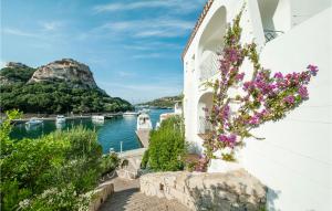 a white building with purple flowers next to a body of water at Trilo 6 in Baja Sardinia +13 photos