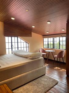 a bedroom with a bed and a table and windows at THE GINGKO EYRIE in Kalimpong