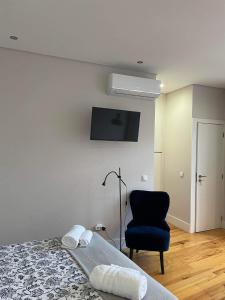 1 dormitorio con 1 cama, 1 silla y TV en C & H Studio, en Guimarães