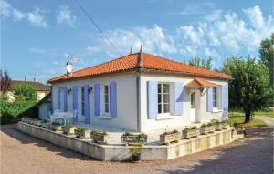a small white house with blue windows and plants at Nice Home In Bassillac With Kitchen in Bassillac
