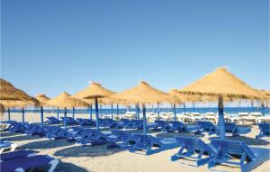 einen Strand mit blauen Stühlen und Strohschirmen in der Unterkunft Gorgeous Home In Roquetas De Mar in Roquetas de Mar + 14 Fotos