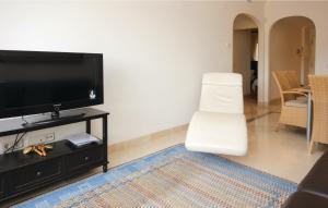 a living room with a flat screen tv and a white chair at 2 Bedroom Lovely Apartment In La Cala De Mijas in La Cala de Mijas