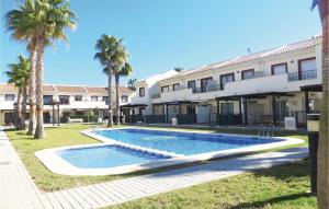a swimming pool in front of a building with palm trees at 2 Bedroom Cozy Home In Ciudad Quesada in Ciudad Quesada